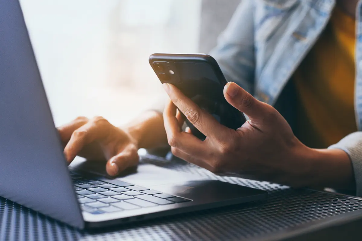 Person holding a phone using a laptop