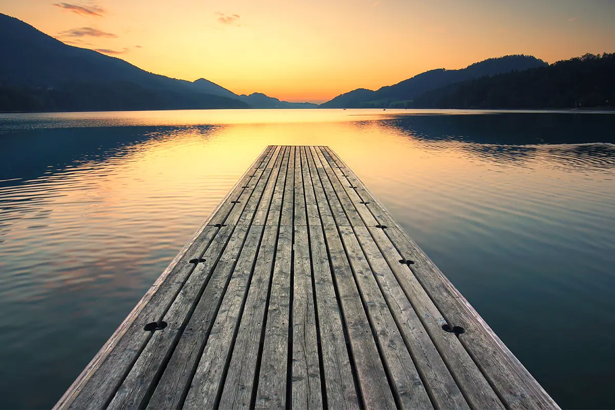 Dock over calm lake at sunset