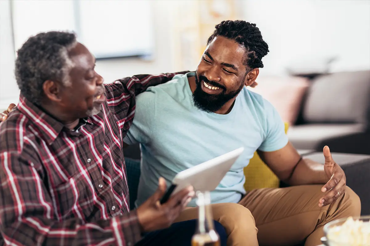 Father and son holding a tablet while sitting on the couch
